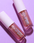 Two lip glosses with glittery finish on a purple background