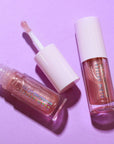 Two lip gloss products on a purple background