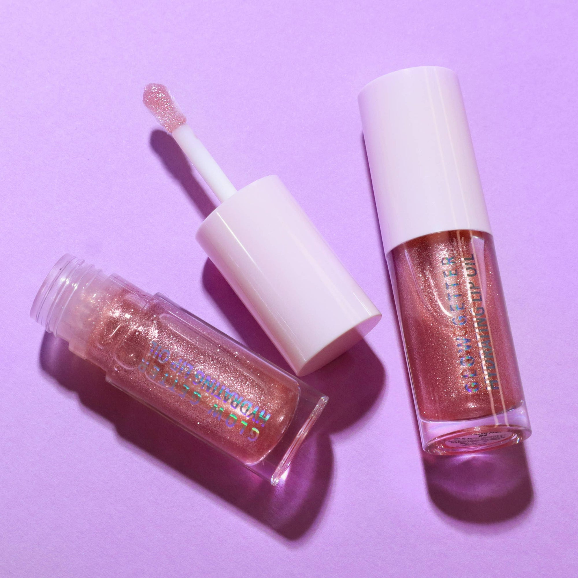 Two lip gloss products on a purple background