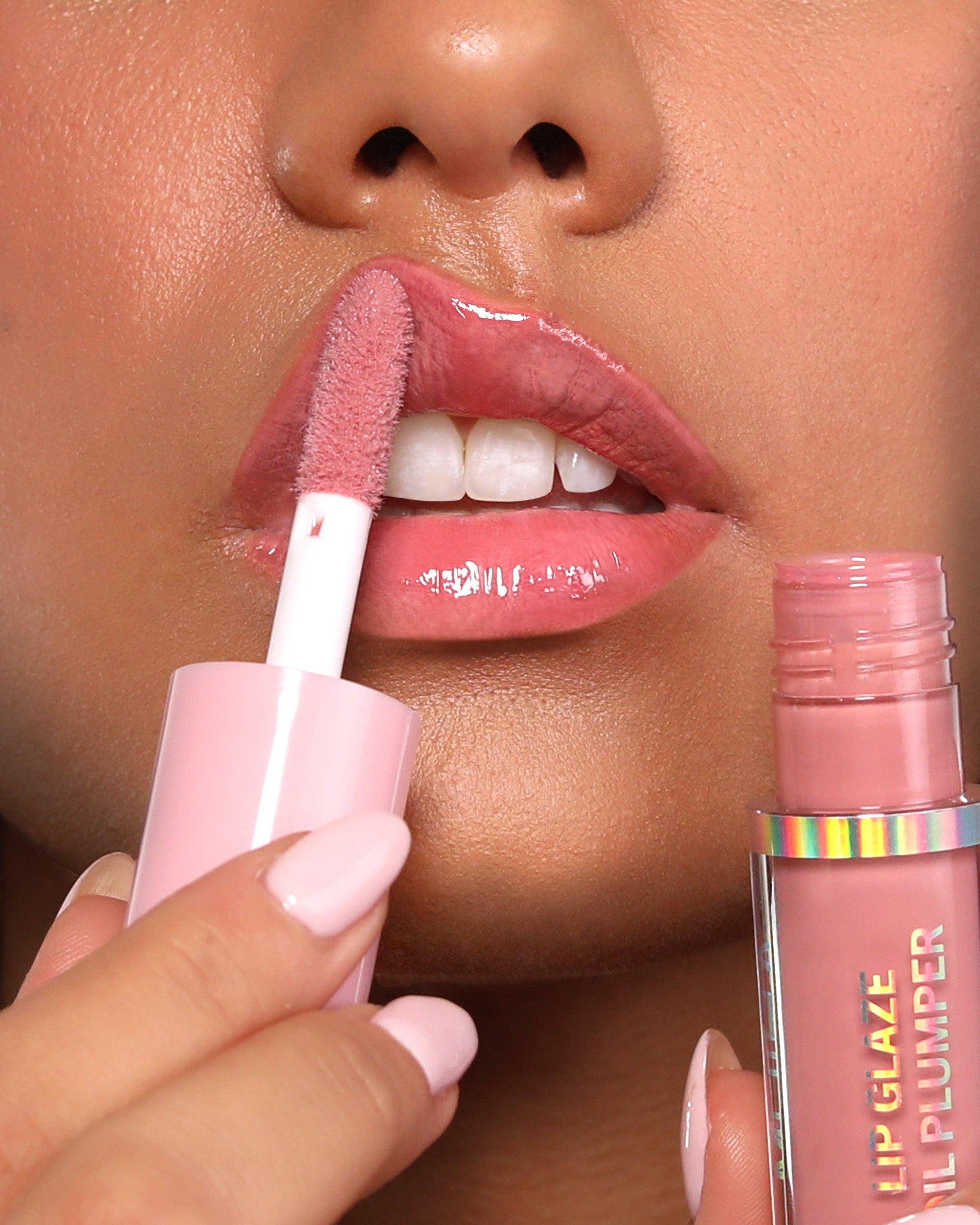 Applying pink lip gloss to their lips with a close-up of the product.